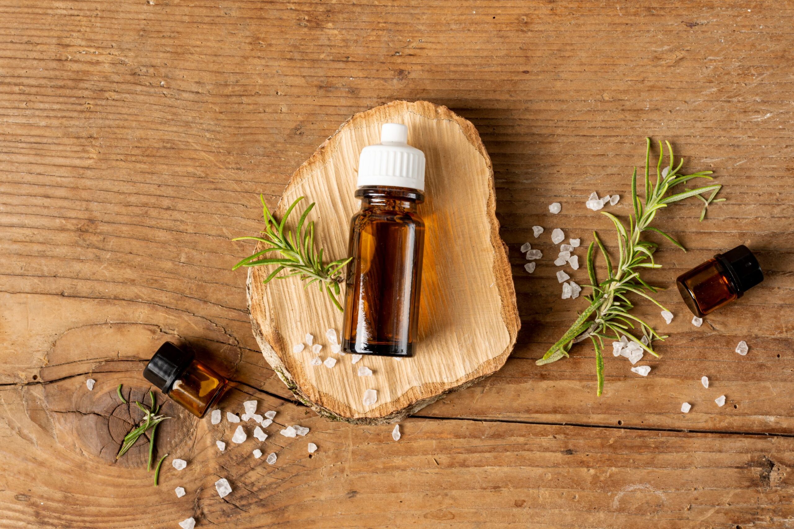 olejek eteryczny i zapachowy - buteleczka olejku na drewnianej podkładce w towarzystwie ziół i soli
